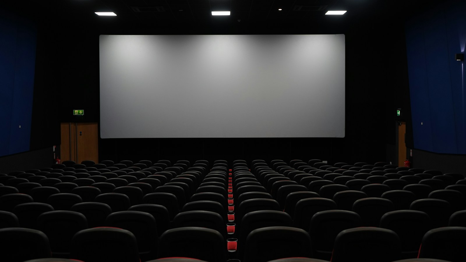 High-end dedicated home theater room featuring acoustic wall treatment panels, luxury recliner seating, and reference audio calibration
